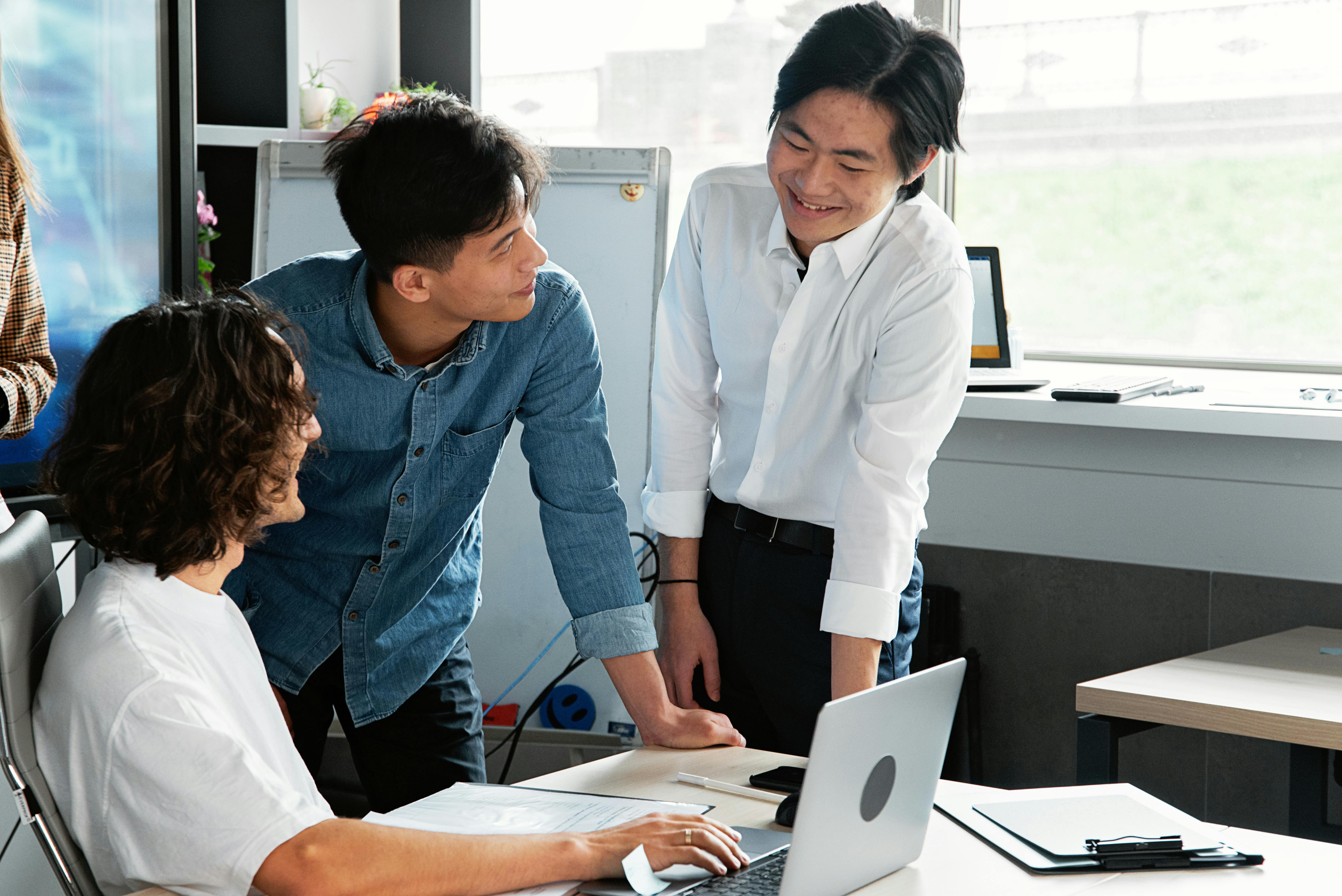 Three colleagues collaborating around a laptop and documents in a bright office. Photo: Mikhail Nilov / Pexels.