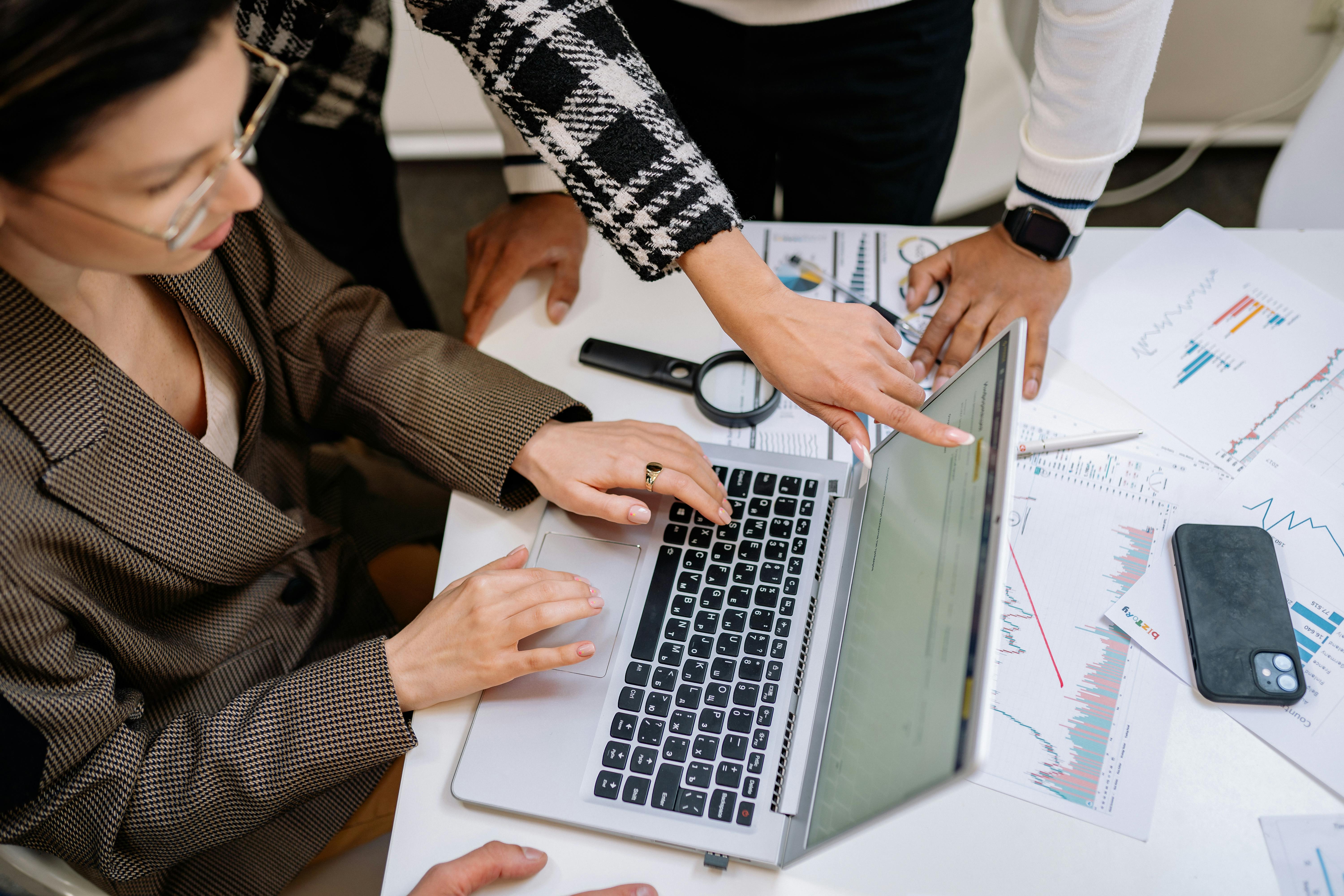 Colleagues reviewing documents and a laptop together at a meeting table. Photo: Yan Krukau / Pexels.