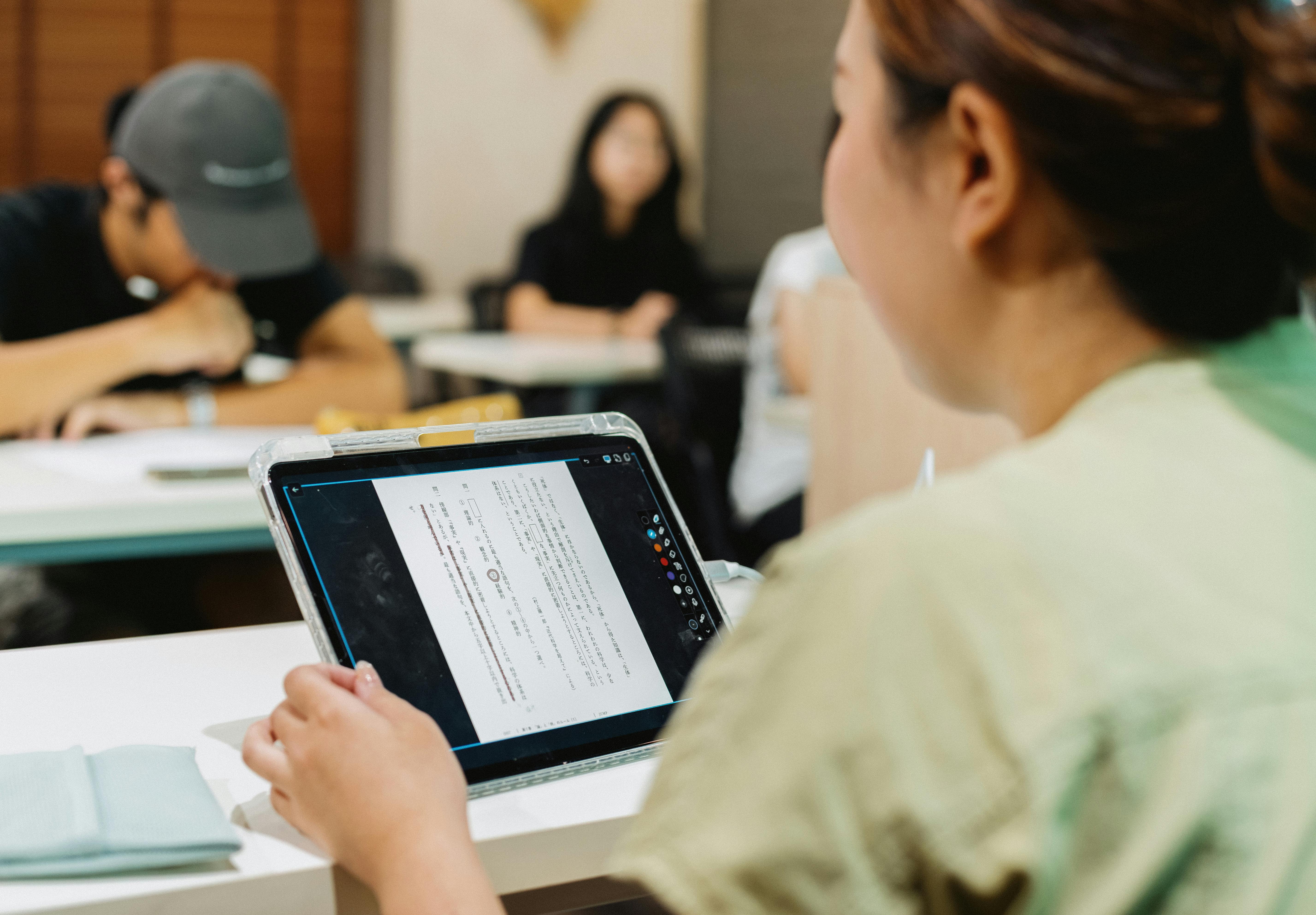 University student working on a laptop on campus with headphones. Photo: Gu Ko / Pexels.