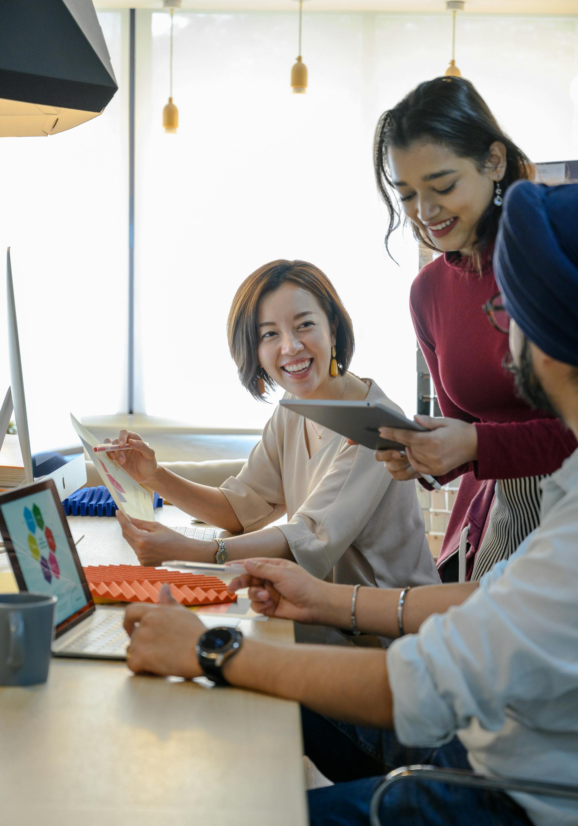 Team collaborating with laptop, tablet, and documents in a bright modern office. Photo: Ketut Subiyanto / Pexels.