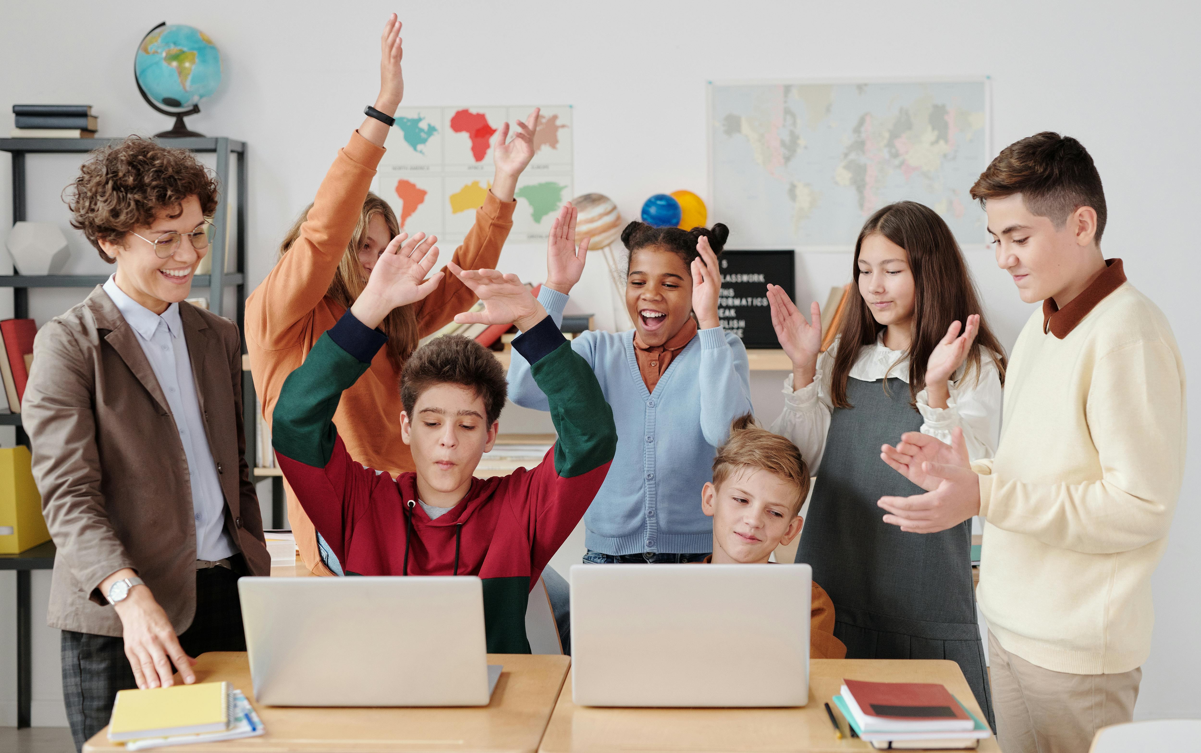 Primary classroom with teacher and students using a wall display. Photo: Max Fischer / Pexels.