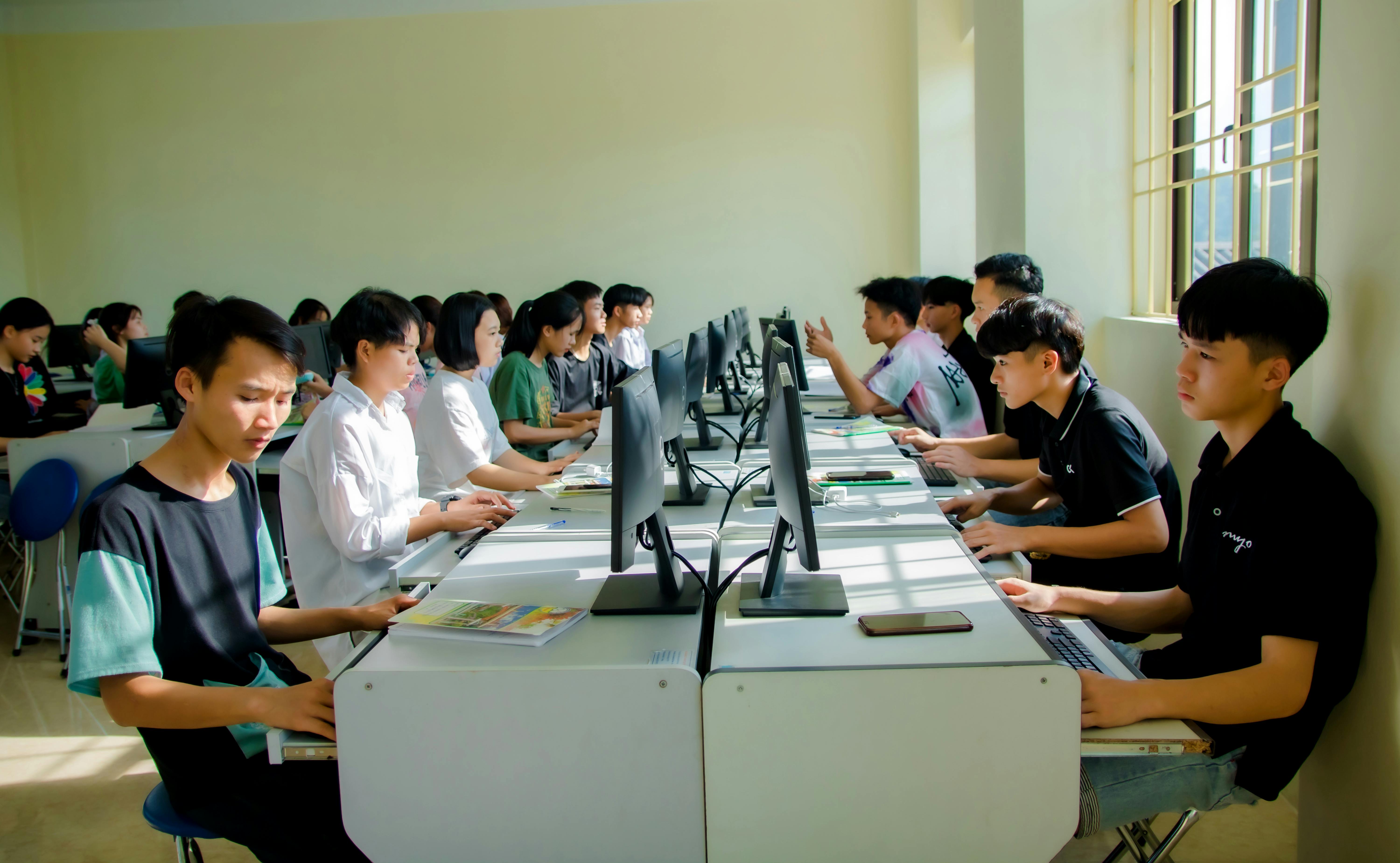 Blended classroom with learners at desks and screens—hybrid teaching context.